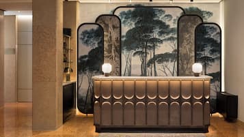 Un comptoir d’accueil au design moderne, agrémenté de lampes murales et d’une grande fresque représentant un arbre.