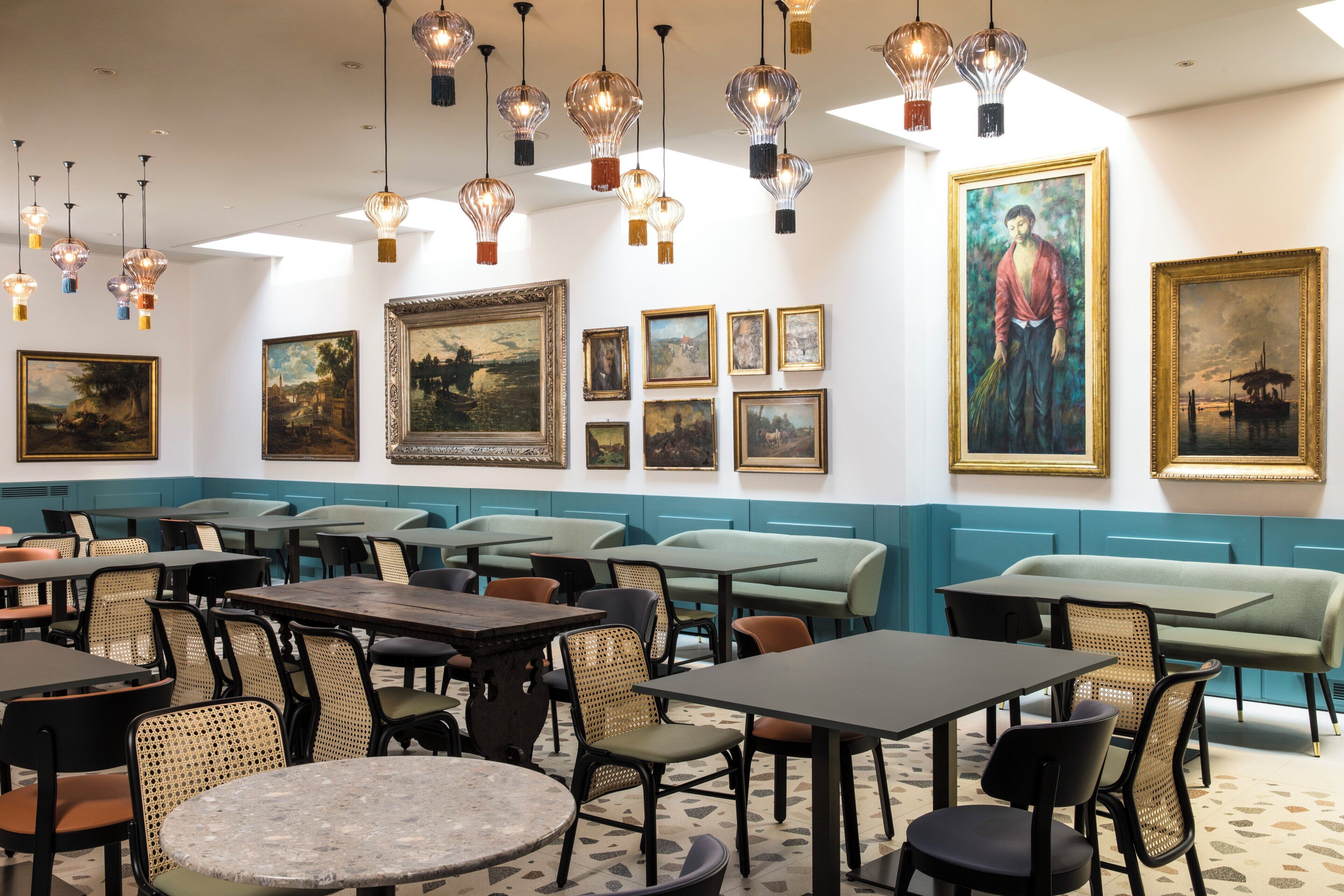 A restaurant interior with tables, chairs, and artwork on the walls.