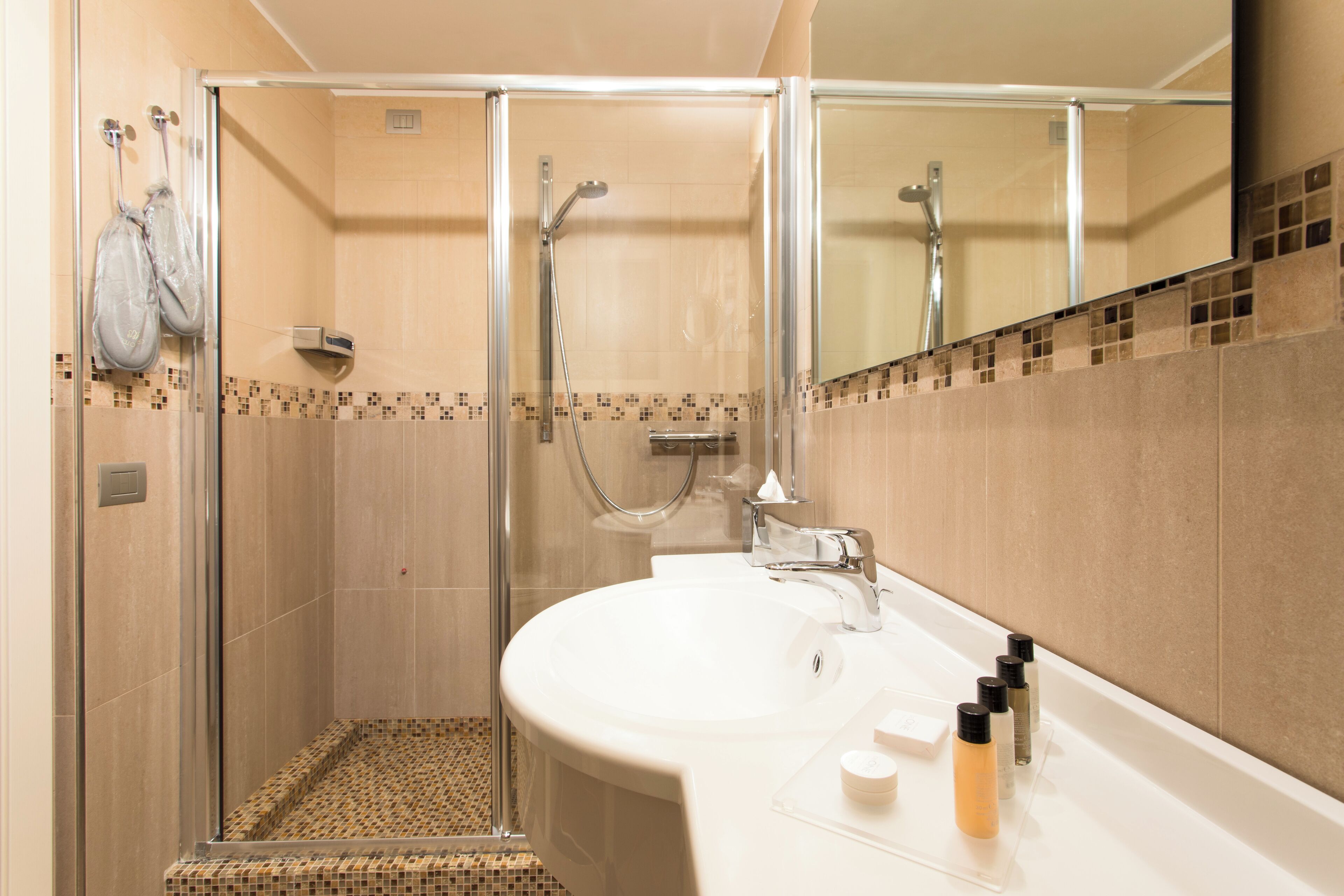 Une salle de bain moderne avec une douche à parois de verre, un lavabo blanc et un miroir au-dessus.