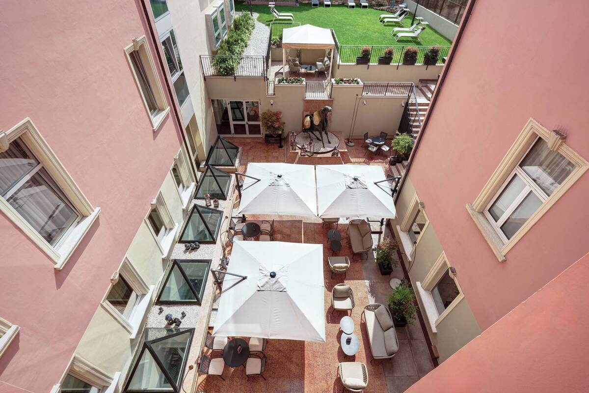 A courtyard with outdoor seating, umbrellas, and a view of a green lawn.