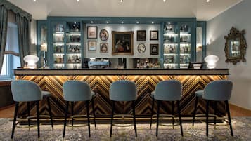 A bar area with a chevron-patterned counter, bar stools, and a collection of framed artworks on the wall.
