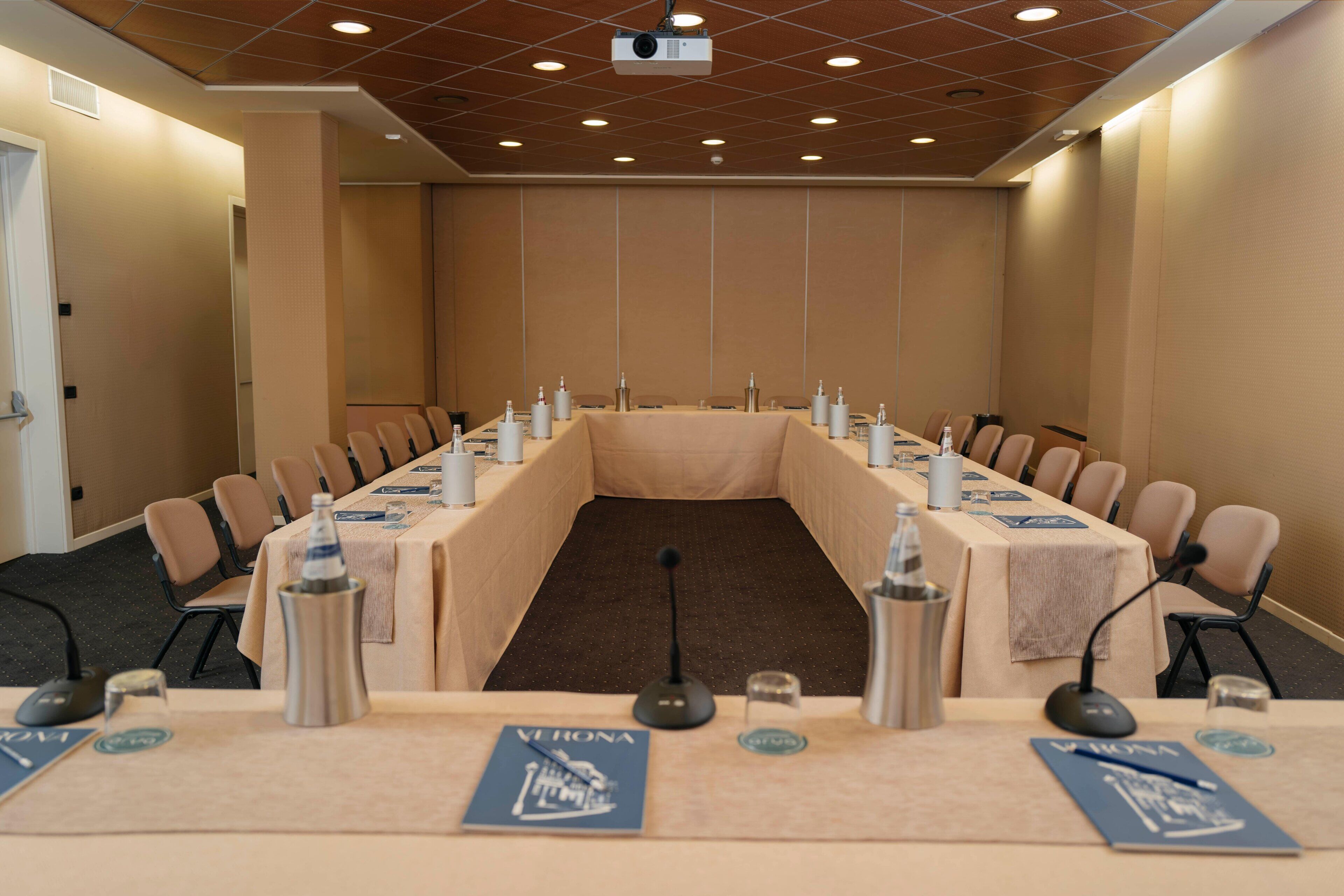 A conference room with a long table, chairs, microphones, and nameplates.