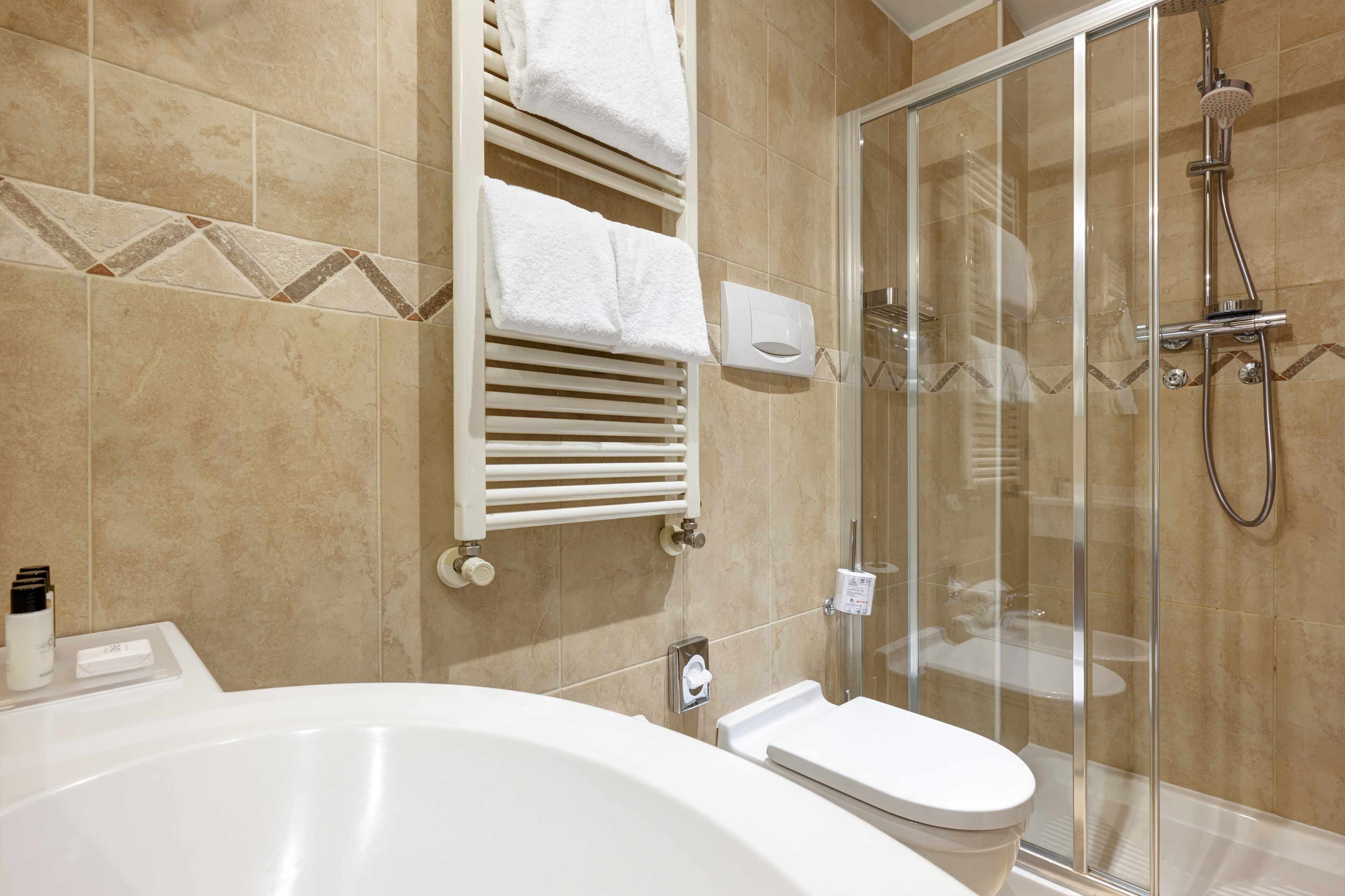 A modern bathroom with a bathtub, toilet, and glass-enclosed shower.