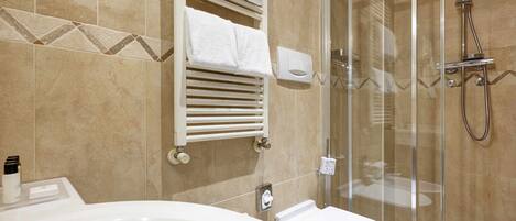 A modern bathroom with a bathtub, toilet, and glass-enclosed shower.
