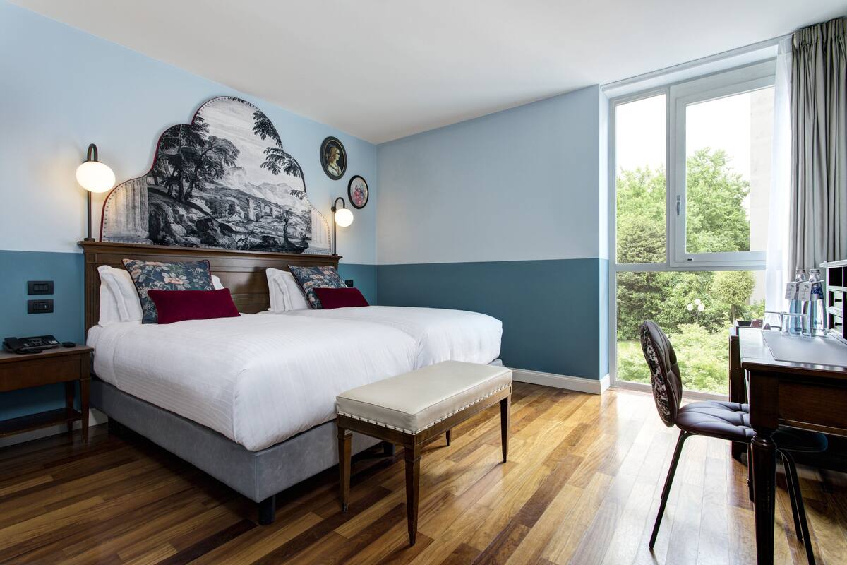 A bedroom with a large bed, a bench, a desk, and a chair.