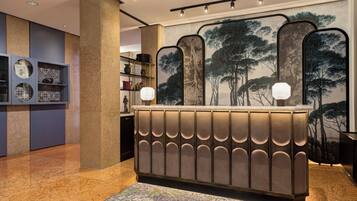 A reception area with a modern design, featuring a central counter with a patterned backrest and two wall-mounted light fixtures.