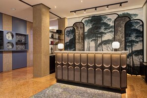 A reception area with a modern design, featuring a central counter with a patterned backrest and two wall-mounted light fixtures.