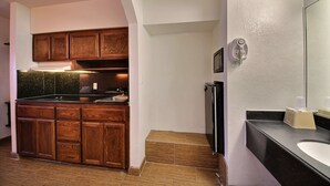 Une cuisine avec des meubles de rangement en bois, un plan de travail noir et un évier.