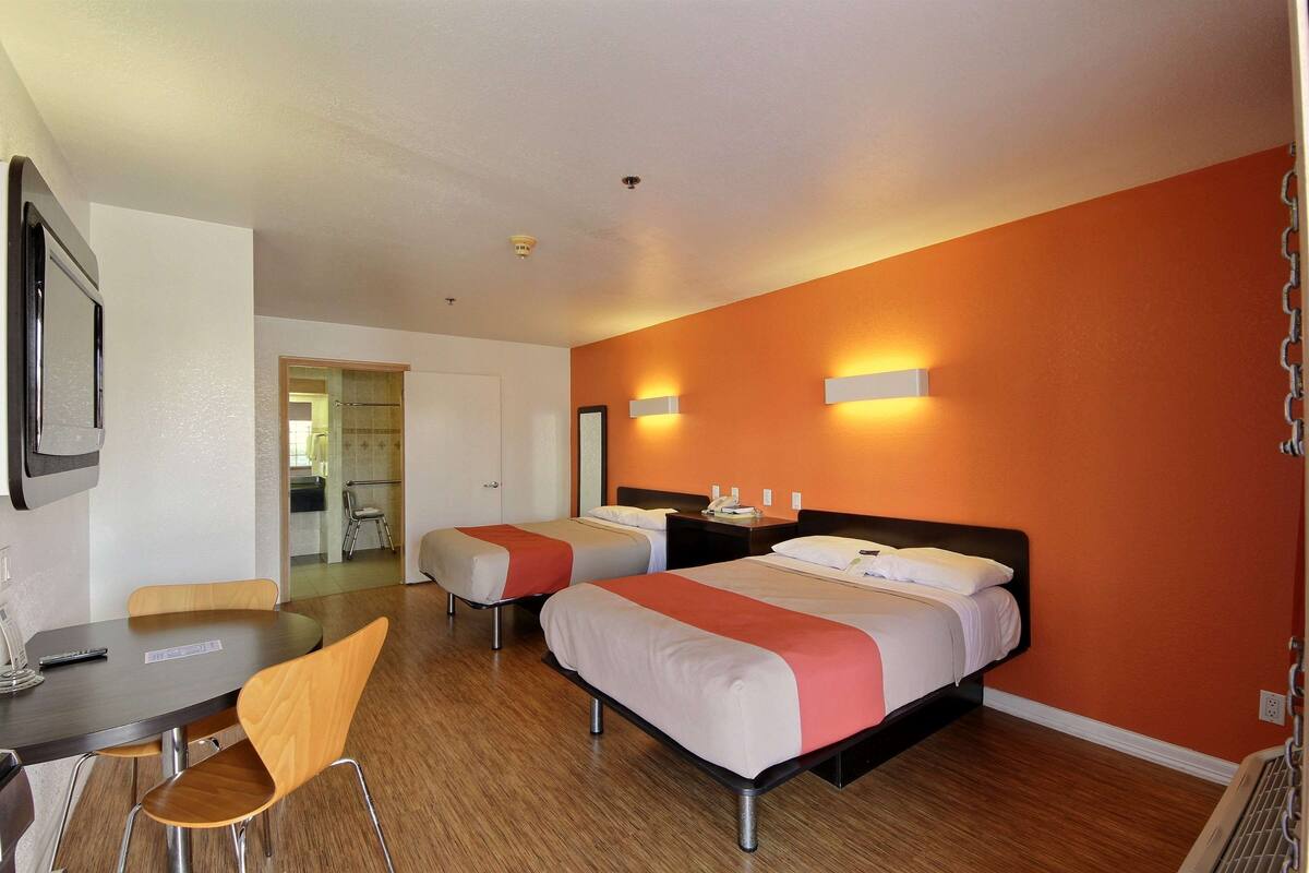 A hotel room with two single beds, a desk, and a chair.