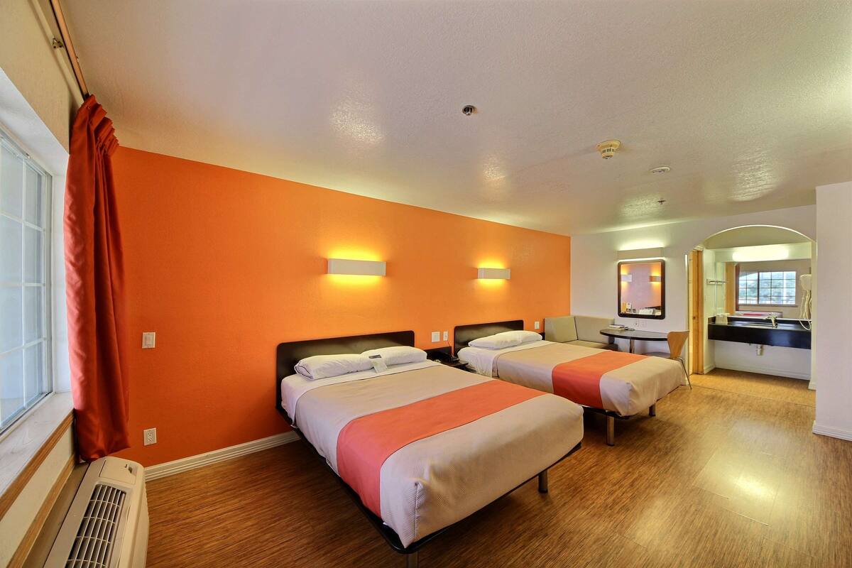 A hotel room with two beds, a bathroom, and a desk.