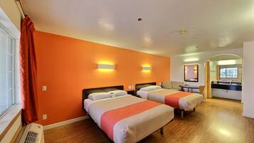 A hotel room with two beds, a bathroom, and a desk.