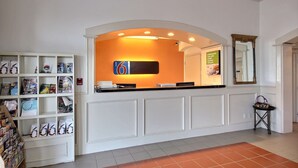 Un espace d’accueil comprenant un comptoir, un panneau indicateur, un miroir et une étagère avec des magazines.