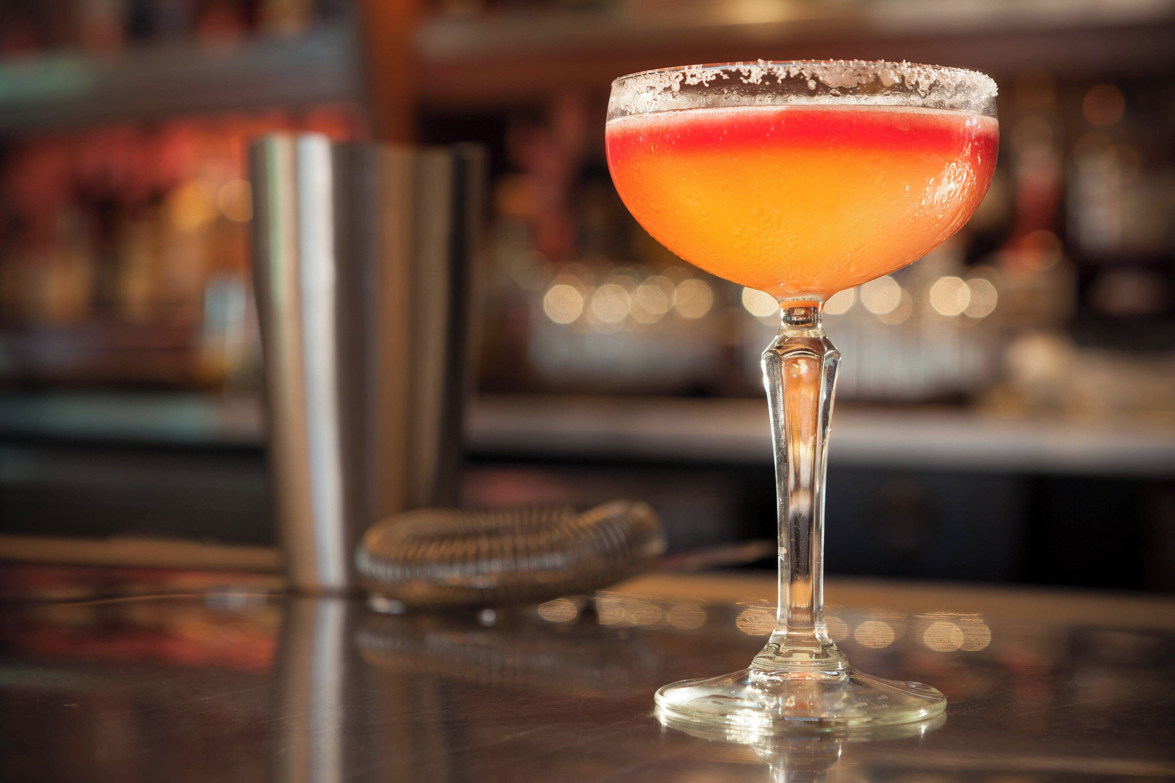 A cocktail glass with a salted rim on a bar counter.
