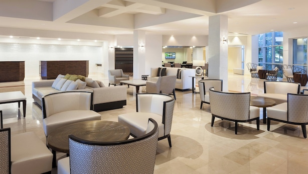 Un hall amplio con varias zonas de estar, incluyendo sofás y sillones, una mesa de centro y un mostrador de recepción.
