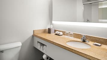 Un baño moderno con un inodoro blanco, un lavabo con un espejo encima y un perchero debajo.