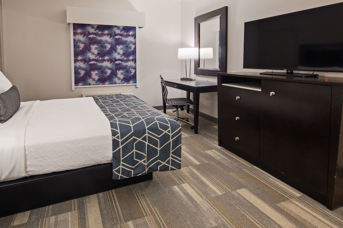 A hotel room with a bed, a desk, a television, and a wardrobe.