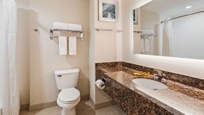 Un baño con inodoro, lavamanos, toallero y espejo.