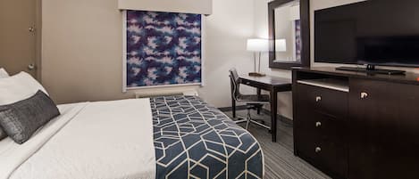 A hotel room with a bed, a desk, a television, and a large window with a view.