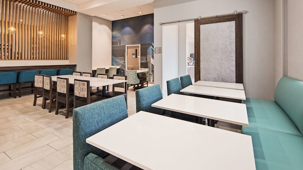 A restaurant with a modern interior, featuring wooden panel walls, blue upholstered booths, and white tables. - Best Western Plus Wilkes Barre-Scranton Airport Hotel (Avoca)