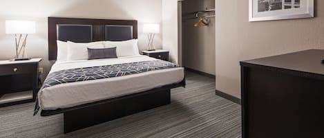 A hotel room with a bed, bedside tables, a desk, and a framed picture on the wall.