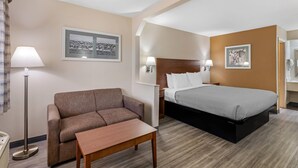 A hotel room with a bed, a sofa, a small table, and two wall-mounted lamps. - Quality Inn & Suites Stockbridge Atlanta South I-75 (Stockbridge)