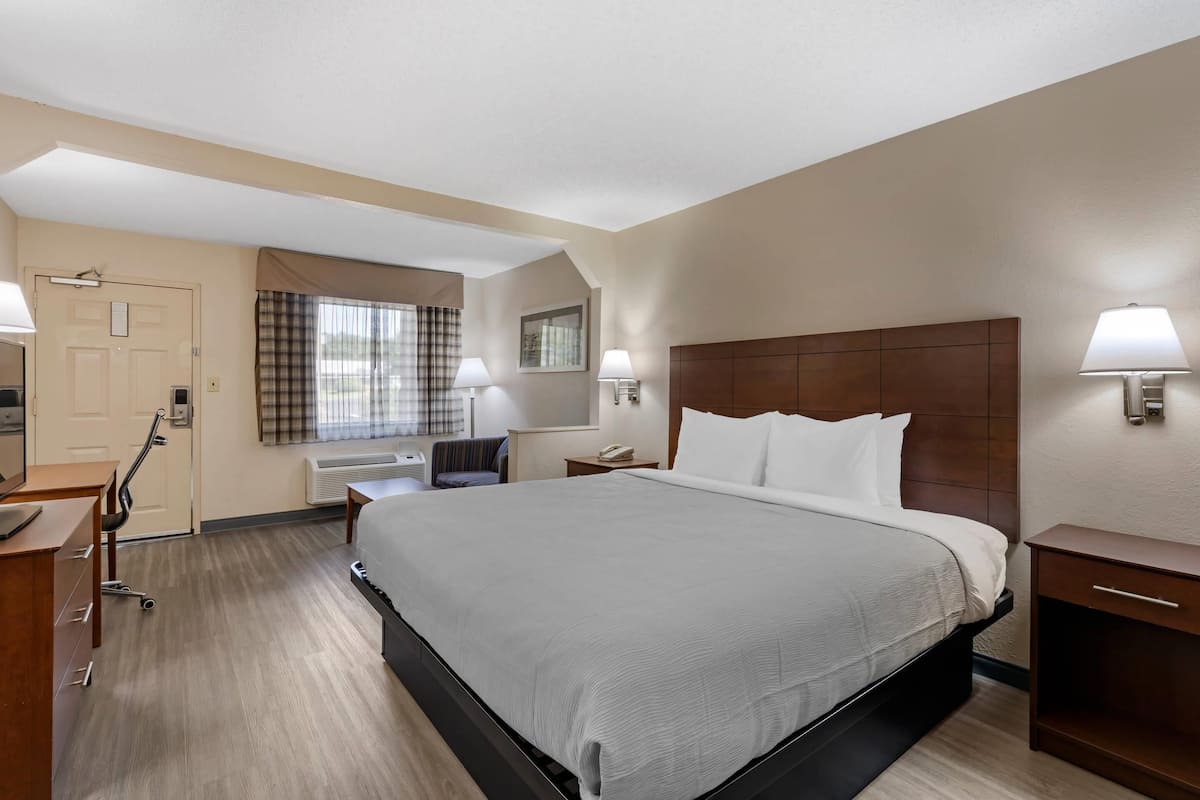 A hotel room with a large bed, bedside tables, a desk, and a chair.