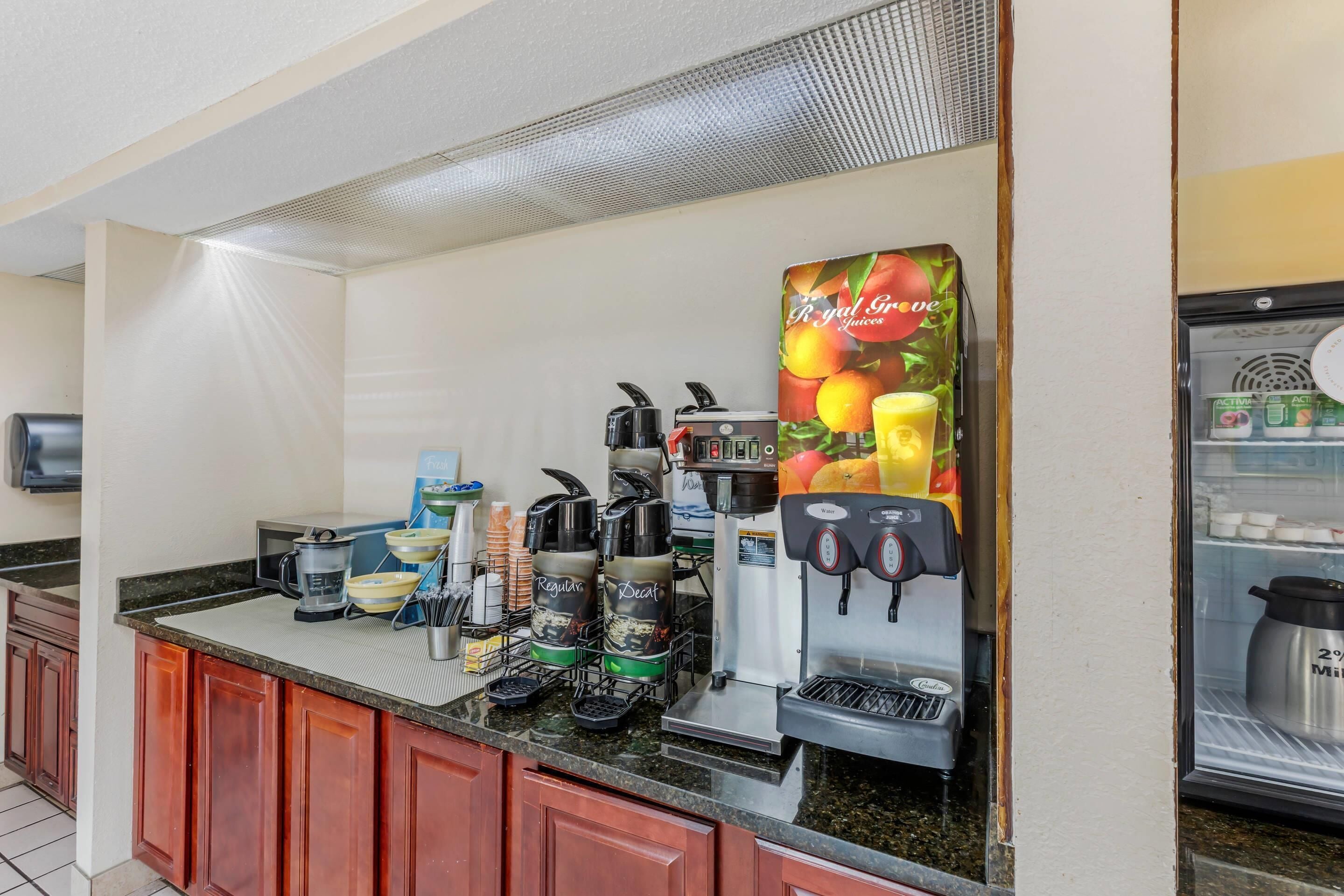 Uma estação de café com várias máquinas de café, um refrigerador e um dispensador de bebidas.