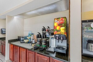Uma estação de café com várias máquinas de café, um refrigerador e um dispensador de bebidas.