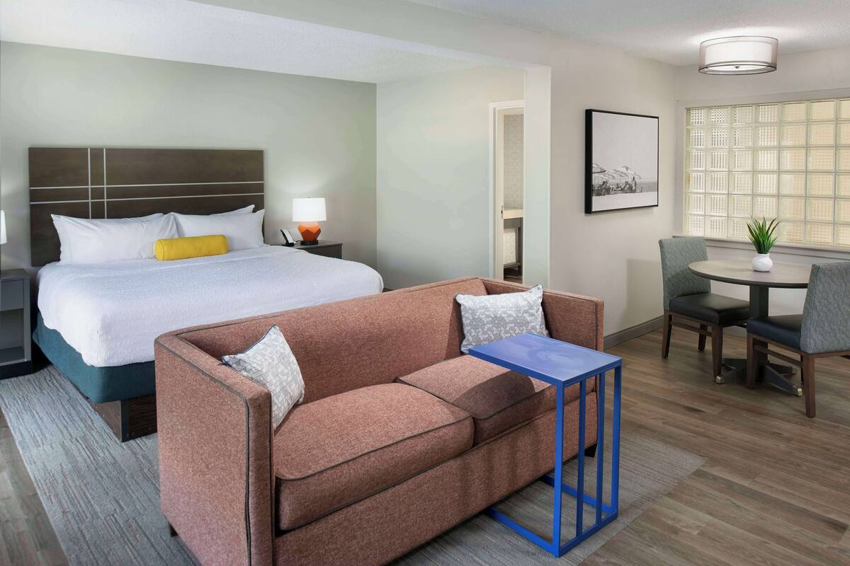 Une chambre d’hôtel moderne dotée d’un grand lit, d’un canapé, d’une petite table et d’un coin repas avec des chaises.