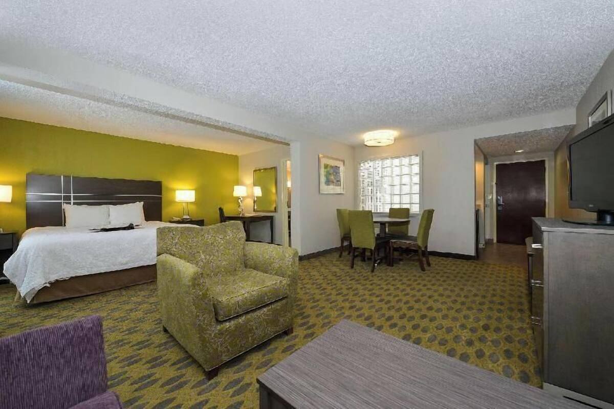 Une chambre d’hôtel avec un lit, une chaise, une table, un téléviseur et un bureau avec une lampe.