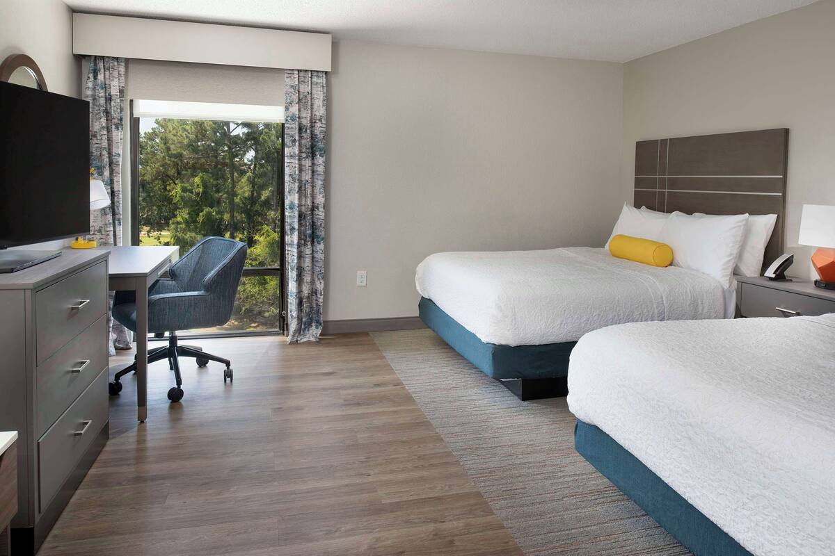 Une chambre d’hôtel avec deux lits, un bureau et une chaise.