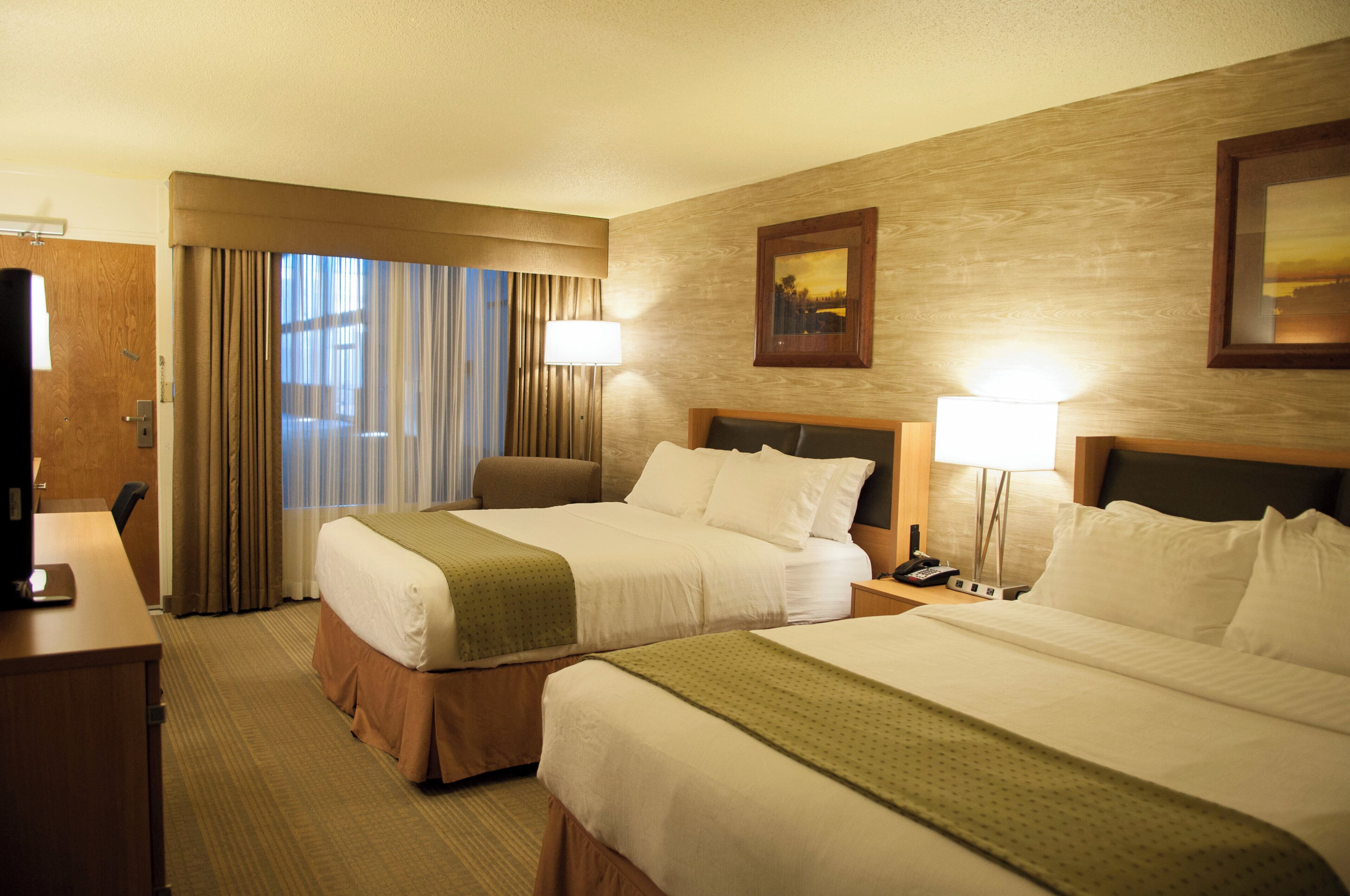 Ein Hotelzimmer mit zwei Betten, einem Schreibtisch und einem Stuhl.