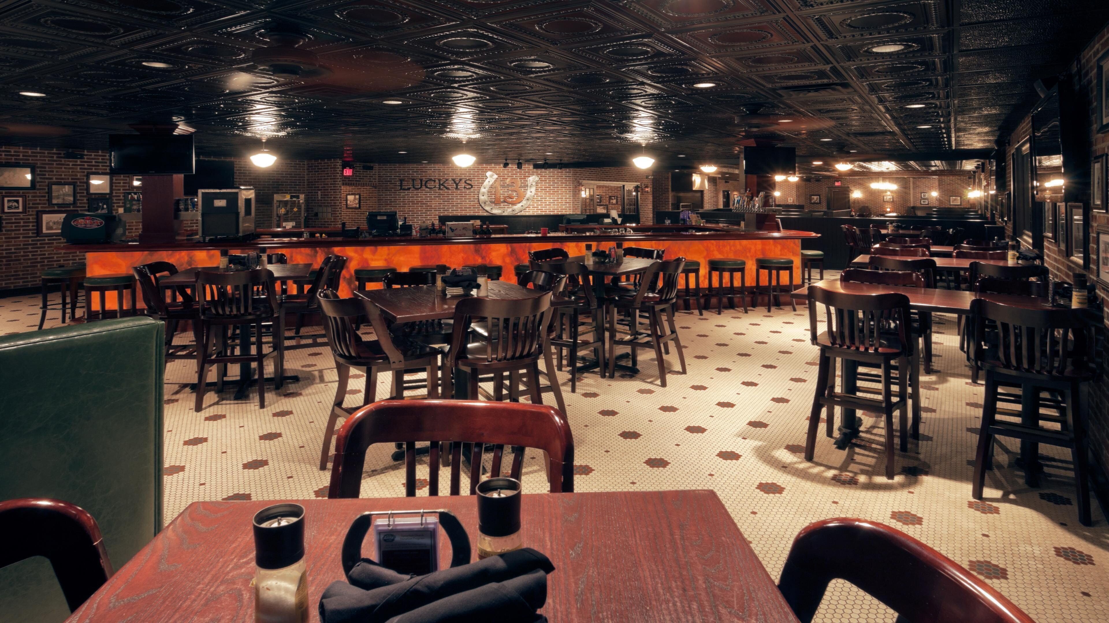 A restaurant interior with brick walls, a bar area, and multiple seating arrangements.