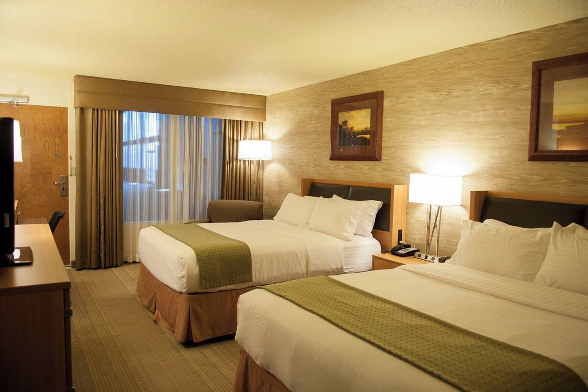 Habitación de hotel con dos camas, un escritorio y una silla.