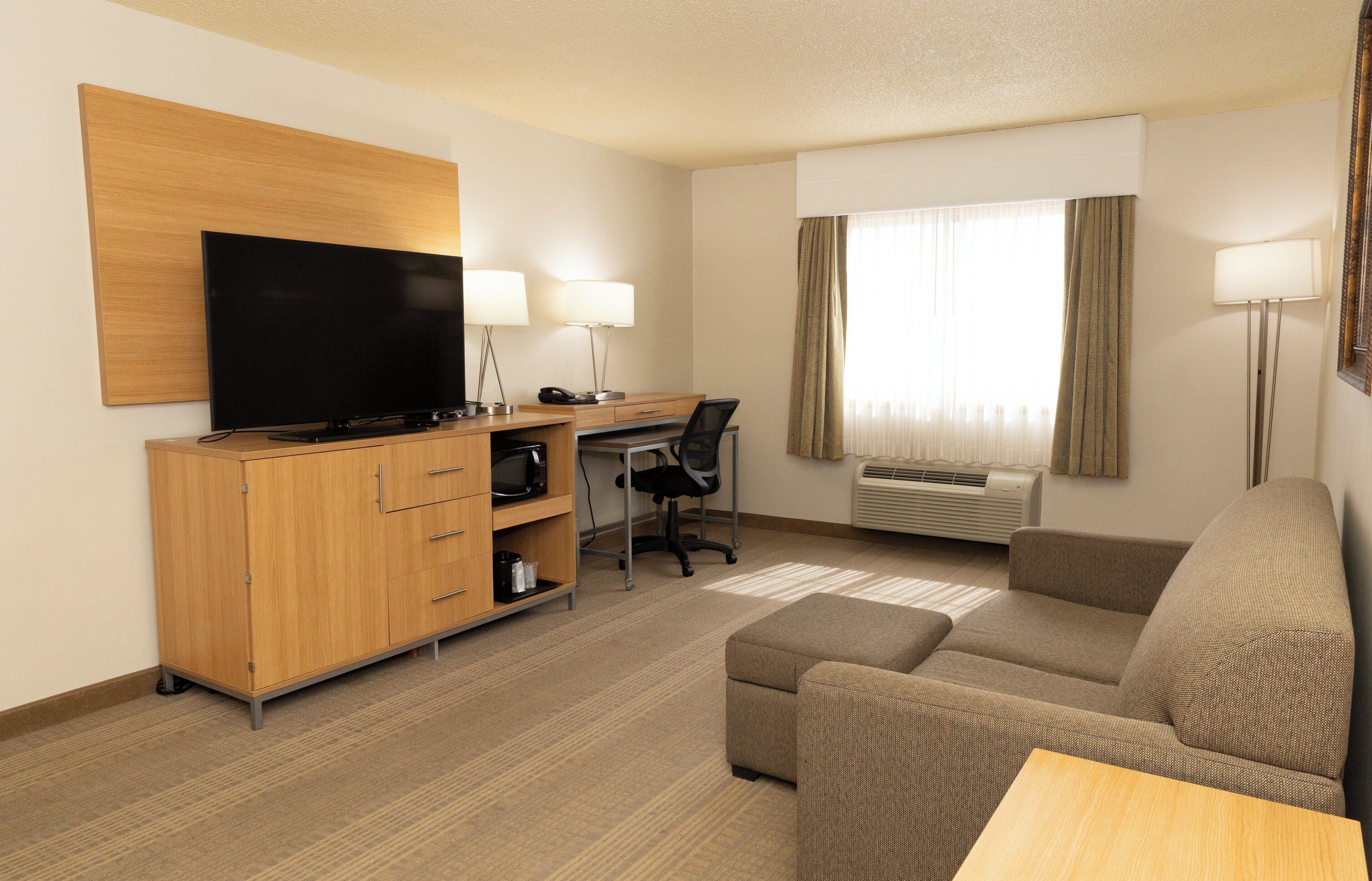 Een hotelkamer met een houten bureau, een televisie, een bank en een lamp.