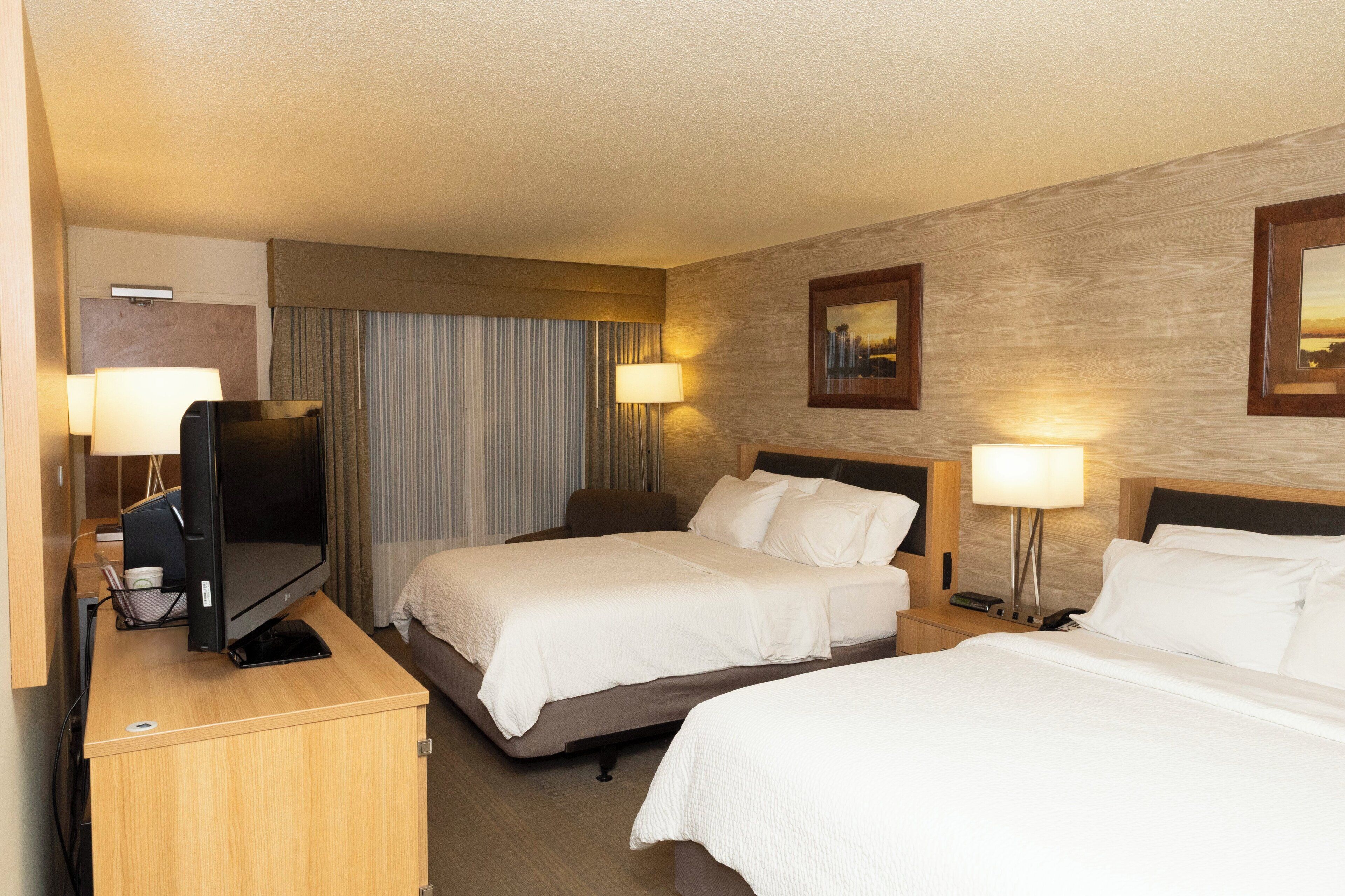 Una habitación de hotel con dos camas, un escritorio con ordenador y televisión.