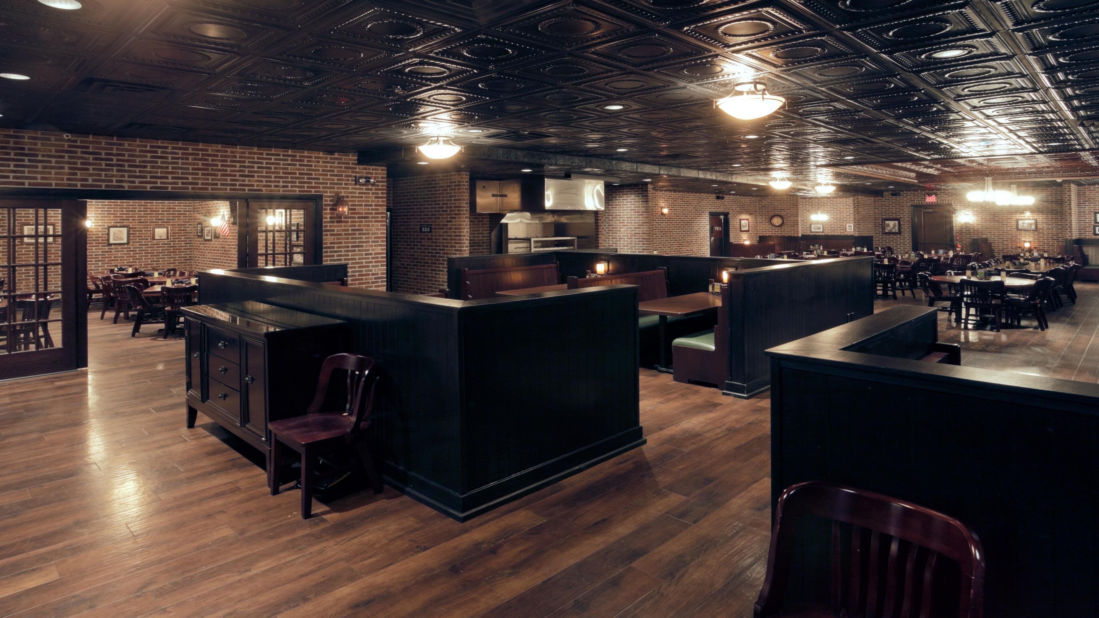 Un interior de restaurante con paredes de ladrillo, piso de madera y una zona de bar.