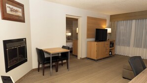 A hotel room with a dining area, a TV, a fireplace, and a view of the room. - Holiday Inn Spearfish - Convention Center by IHG (Spearfish)