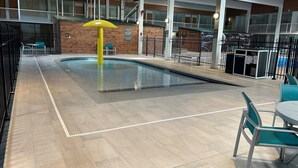 An indoor swimming pool with a yellow umbrella, surrounded by a tiled floor and a wooden deck area. - Holiday Inn Spearfish - Convention Center by IHG (Spearfish)