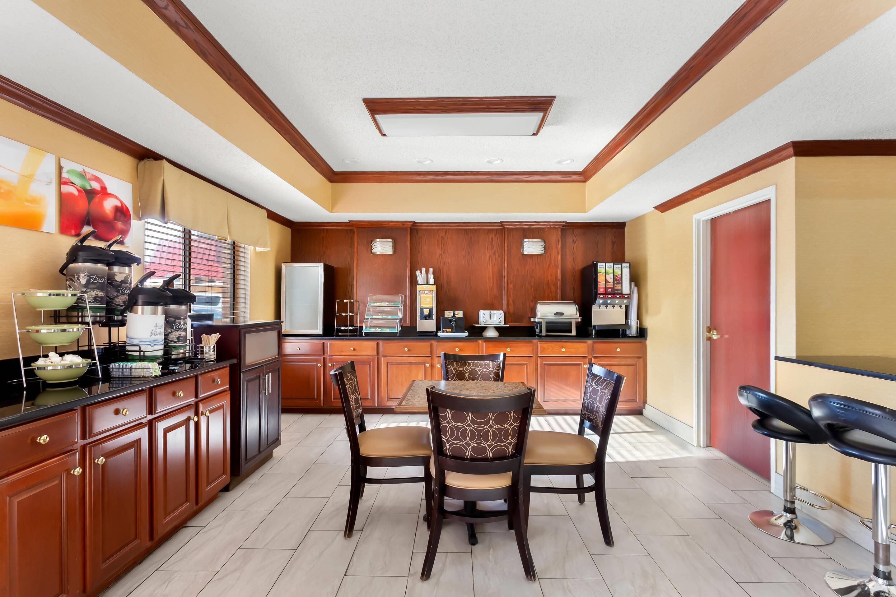 A modern kitchen with wooden cabinets, a dining table with chairs, and a red door.
