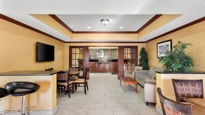 Amplia sala de estar con una cocina al fondo, una zona de bar con taburetes y un área de descanso con sofás y sillones.
