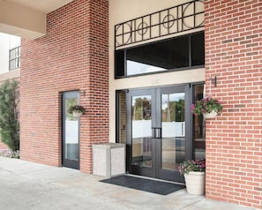 A brick building with a double door entrance, a small planter with flowers, and a number '1265' above the door. - Quality Inn & Suites Niles (Niles)
