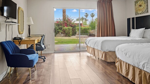 A hotel room with a bed, a desk with a chair, a TV, and a view of the outdoors.