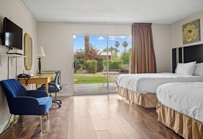 Habitación de hotel con cama, escritorio con silla, televisor y vistas al exterior.