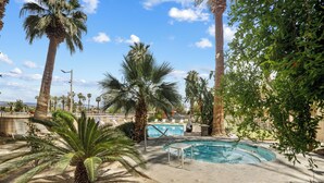 A pool area with palm trees, a swimming pool, and a lounge chair.