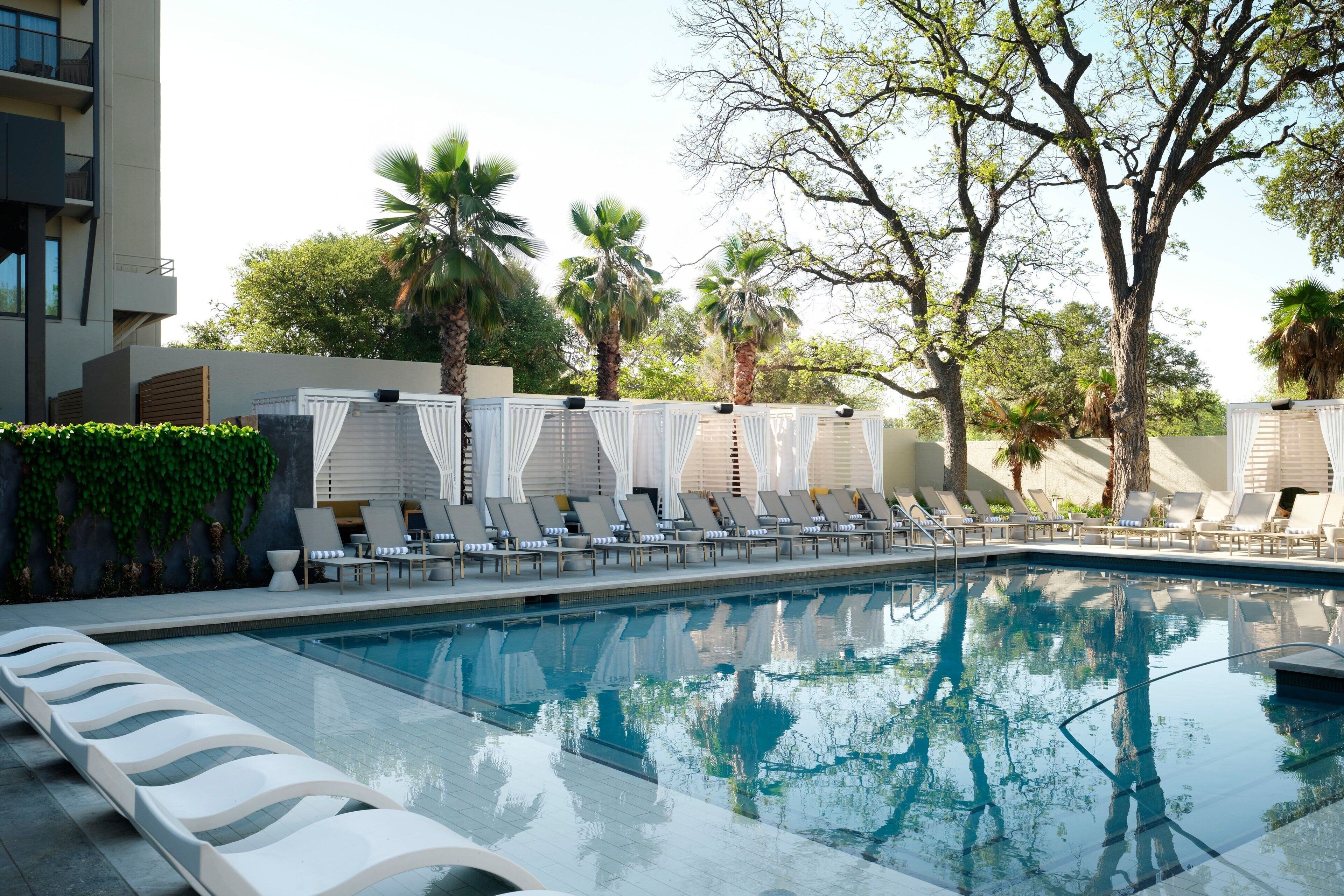 A swimming pool with lounge chairs and palm trees.