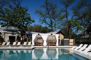 Un área de piscina con sillas de descanso y una zona de estar cubierta.