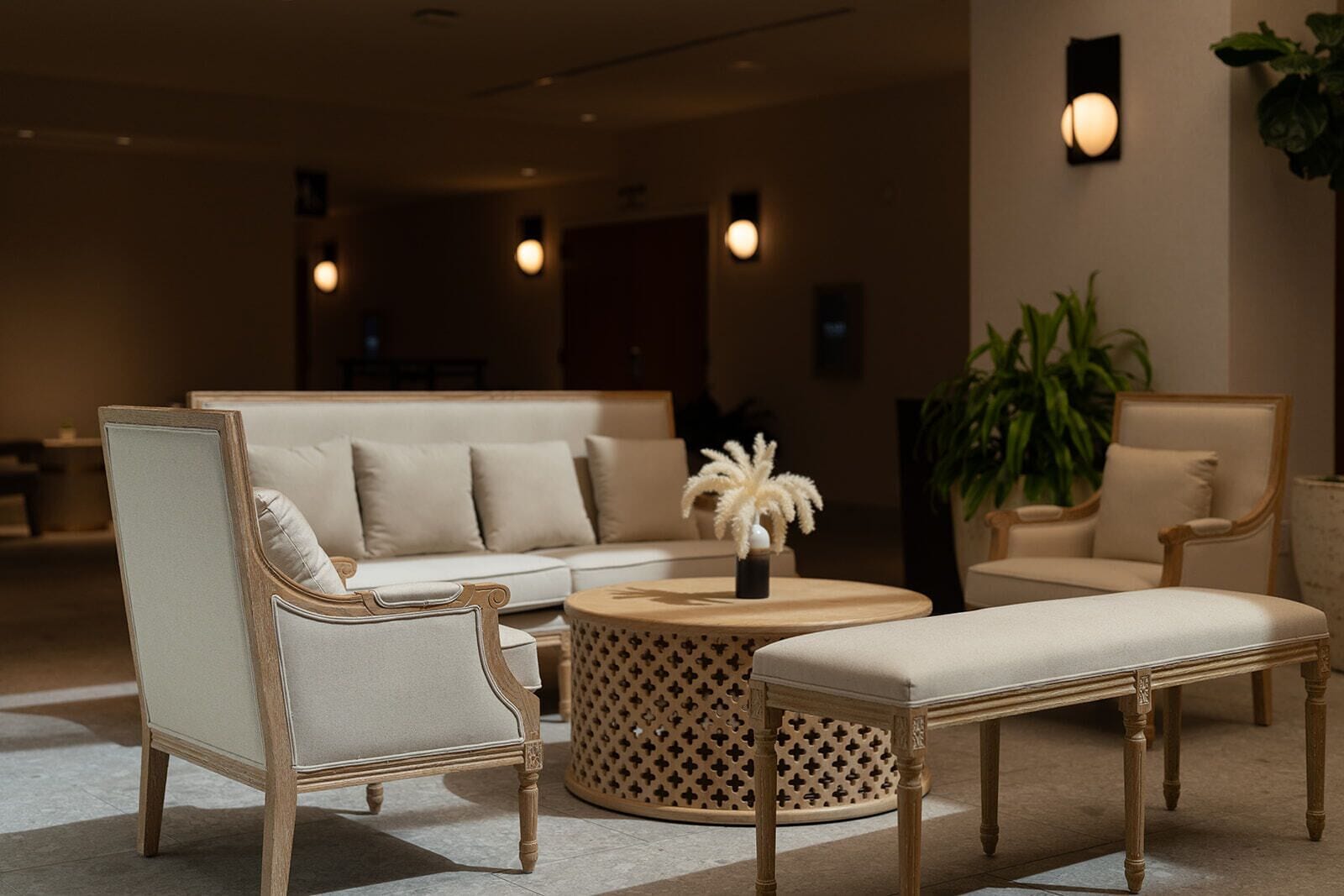A modern lounge area with a sofa, armchairs, a round coffee table, and a bench.