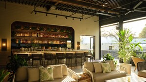 A bar area with a variety of bottles, bar stools, and a seating area with sofas and tables.