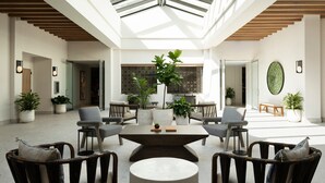 A spacious lobby with a high ceiling, modern furniture, and potted plants.